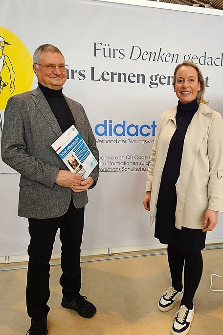 Ein Mann und eine Frau stehen vor einer Wand mit der Aufschrift "didacta". Der Mann hat eine Zeitschrift in der Hand. Die Zeitschrift hat den Titel "blind - sehbehindert". 